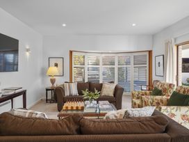 A living room with brown sofas floral armchairs a coffee table with a chessboard and books at Stylish Fendalton Townhouse - Prime Location in Christchurch