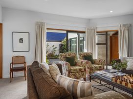 A living room with sofas chairs a coffee table with books and a chess set at Stylish Fendalton Townhouse - Prime Location in Christchurch