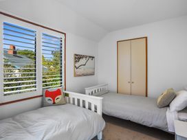 A bedroom with two single beds a window with shutters and a closet at Stylish Fendalton Townhouse - Prime Location Christchurch