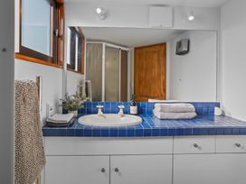 A bathroom with a blue tiled countertop sink a large mirror a wooden door and a shower at Stylish Fendalton Townhouse - Prime Location in Christchurch