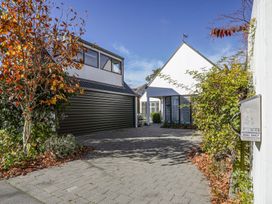 Driveway with brick paving leading to a modern white house and garage with trees and bushes at Stylish Fendalton Townhouse Prime Location Christchurch