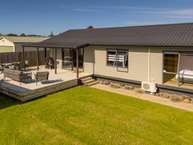 A deck with chairs and table at Seabreeze Surf House - Whitianga