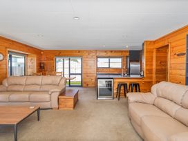 A living room with sofas and kitchen counter at Seabreeze Surf House - Whitianga Escape, Whitianga