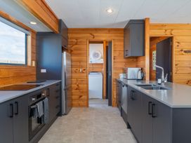 A kitchen with cabinets and appliances at Seabreeze Surf House - Whitianga