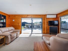 A snug with a sofa and television at Seabreeze Surf House - Whitianga
