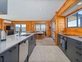 A kitchen with appliances and dining area at Seabreeze Surf House - Whitianga Escape