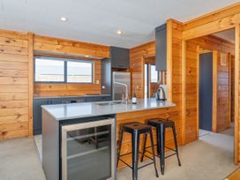 A kitchen with counter and stools at Seabreeze Surf House - Whitianga