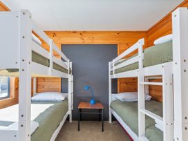 A bedroom with bunk beds and a blue desk lamp at Seabreeze Surf House - Whitianga Escape, Whitianga