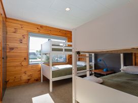 A bedroom with bunk beds and a bedside table at Seabreeze Surf House - Whitianga