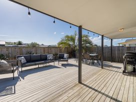An outdoor seating area with furniture and a grill at Seabreeze Surf House - Whitianga