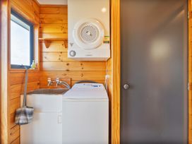 A laundry room with a washing machine, dryer, and sink at Seabreeze Surf House - Whitianga