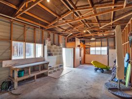 A garage with shelves and storage for multiple items at Seabreeze Surf House - Whitianga