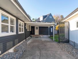 A carport with a concrete driveway and gravel borders between two houses at Waterside Bliss Taupo Central