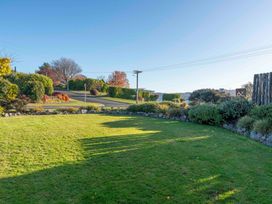 A lawn with bushes and trees near a road with a clear sky at Waterside Bliss Taupo Holiday Home in Taupo Central