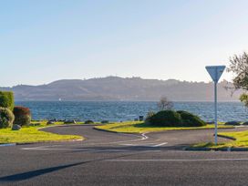 A road with a yield sign next to a body of water and hills in the background at Waterside Bliss Taupo Holiday Home in Taupo Central