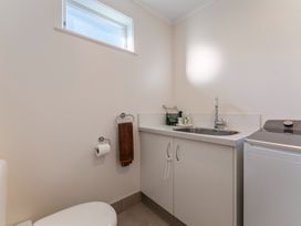A laundry room with a washing machine a sink cabinet a small window and a towel holder with a brown towel at Waterside Bliss - Taupo Holiday Home Taupo Central