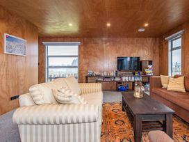 A living room with striped sofa brown sofa wooden coffee table and bookshelf with TV at Mountain Haus Ohakune