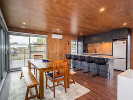 A dining area with wooden table and chairs next to a kitchen with a long island and bar stools at Mountain Haus - Ohakune Holiday Home Ohakune