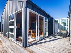 An outdoor wooden deck area with sliding glass doors leading into a dining room at Mountain Haus - Ohakune Holiday Home in Ohakune