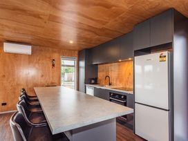 A kitchen area with a long countertop and black chairs along one side at Mountain Haus - Ohakune Holiday Home in Ohakune