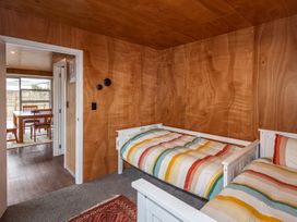 A bedroom with two white single beds with striped bedding and wooden panel walls at Mountain Haus  Ohakune