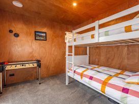 A bedroom with a white bunk bed, foosball table, and wooden walls at Mountain Haus - Ohakune Holiday Home in Ohakune
