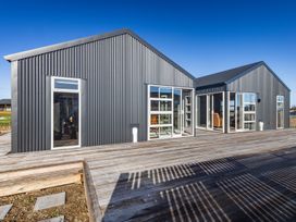 An exterior view of a modern dark grey corrugated metal building with multiple windows and a wooden deck in front at Mountain Haus - Ohakune Holiday Home in Ohakune