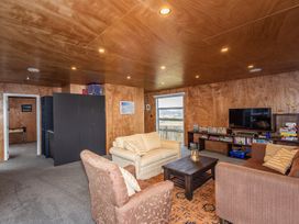 A living room with sofas a coffee table a TV on a stand and bookshelves at Mountain Haus - Ohakune Holiday Home in Ohakune