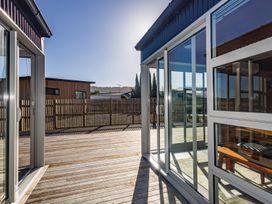 A wooden deck with glass sliding doors and a fence enclosing the yard at Mountain Haus - Ohakune Holiday Home in Ohakune
