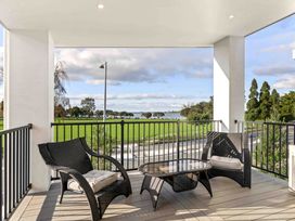 A balcony with chairs and a table overlooking the water at Tauranga Holiday Home in Tauranga
