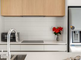 A kitchen with a microwave, refrigerator, and flowers in a vase at Tauranga Holiday Home, Tauranga