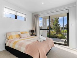 A bedroom with a bed and windows at Tauranga Holiday Home in Tauranga