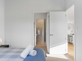 A bedroom with a bed and two open doors leading to a bathroom and kitchen at Tauranga Holiday Home in Tauranga