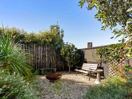 A garden with a bench, table, and plants at Island Views - Waihi Beach Holiday Home