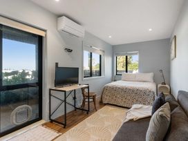 A bedroom with a bed and television at Island Views - Waihi Beach