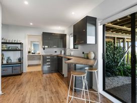 A kitchen with a counter and stools at Island Views - Waihi Beach Holiday Home Waihi Beach