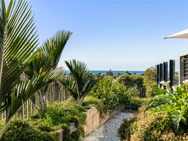 A view of palm trees and ocean from a garden at Island Views - Waihi Beach Holiday Home Waihi Beach