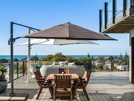 An outdoor area with a table and chairs overlooking the ocean at Island Views - Waihi Beach Holiday Home, Waihi Beach