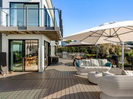 An outdoor deck with seating and umbrellas at Island Views - Waihi Beach Holiday Home Waihi Beach