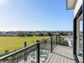 A balcony with a view overlooking the ocean and houses at Island Views - Waihi Beach