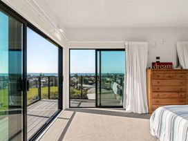 A bedroom with a glass door leading to a balcony at Island Views - Waihi Beach Holiday Home Waihi Beach