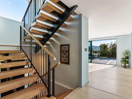 A staircase with a handrail and framed artwork at Island Views - Waihi Beach Holiday Home, Waihi Beach
