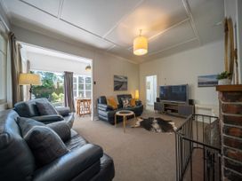 A living room with a sofa, table, and television at Fiordland Hideaway - Te Anau