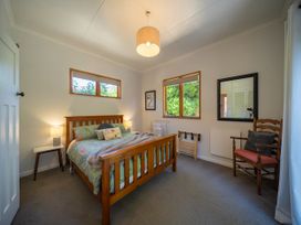 A bedroom with a bed, bedside table and chairs at Fiordland Hideaway - Te Anau