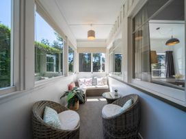 A conservatory with a sofa and chairs at Fiordland Hideaway - Te Anau