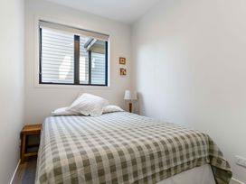 A bedroom with a bed and lamp at Waihi Beach Holiday Home in Waihi Beach