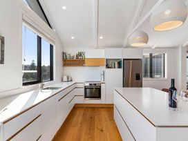 A kitchen with cabinets, sink, oven, and windows at Waihi Beach Holiday Home in Waihi Beach