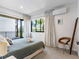 A bedroom with a bed and a chair at Waihi Beach Holiday Home in Waihi Beach