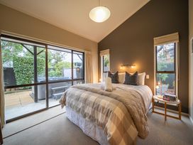 A bedroom with a bed and windows leading to an outdoor patio at Te anau holiday home in Te Anau