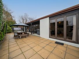 An outdoor area with a table and chairs under an umbrella at Te anau holiday home in Te Anau